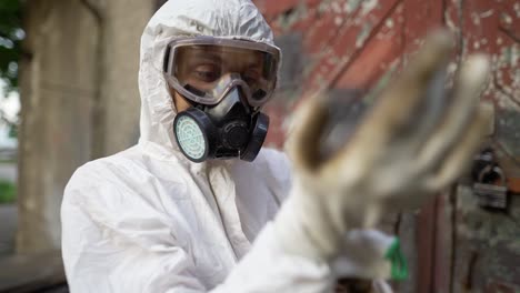 male worker in protective mask putting on gloves outdoors