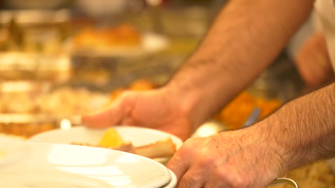 Hands serving food at a self-service buffet