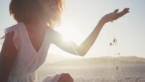 african american woman playing with sand at beach