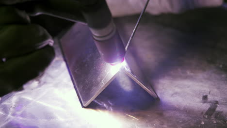 close up of welder wearing protective gloves working in factory