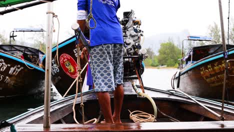 man operating boat engine in krabi, thailand