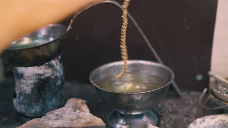 jeweler-cleans-chain-with-water-on-table-in-shop-closeup