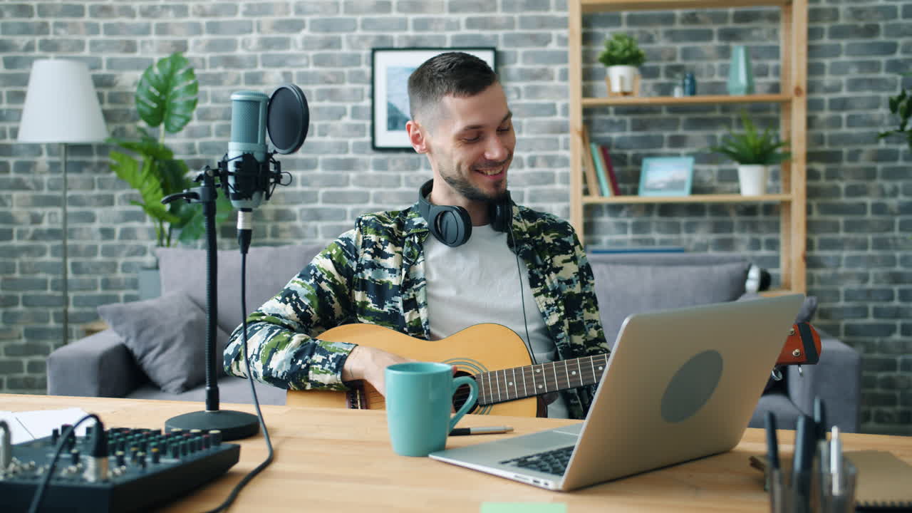 Man playing guitar and recording music at home