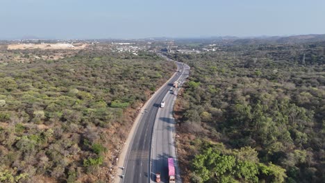 Traffic can be seen moving along the highway, a busy thoroughfare. In the distance, the landscape transitions from developed areas to rolling hills and what appears to be more natural terrain
