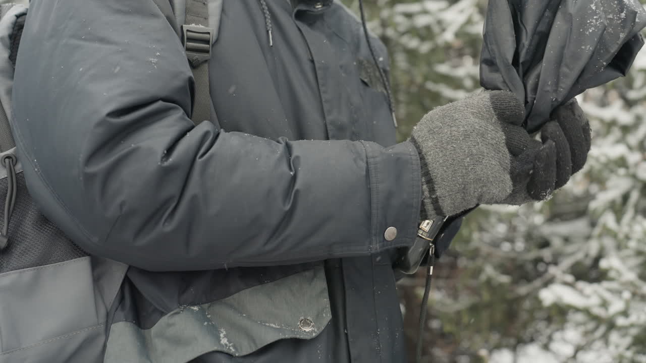 Eine Person richtet sorgfältig die Regenschirmstruktur ein. Jemand manipuliert akribisch Regenschirmspeichen und Stoff. Eine Person passt aufmerksam das Gestell und den Stoff eines kompakten Regenschirms mit Sorgfalt an.
