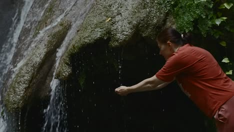 woman drinking water from a waterfall