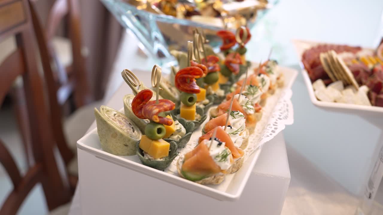 Esposizione di vari snack e stuzzichini disposti su un tavolo. Diversi tipi di cibo sono impilati e serviti agli ospiti durante un evento.