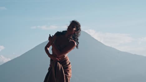 hermosa mujer bailando frente al monte volcánico masivo, tiro a cámara lenta
