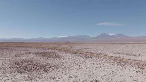 drone shot flying over the dry sand desert mountains in san pedro de atacama chile south america on a blue sky day near mars valley and valley de la luna log