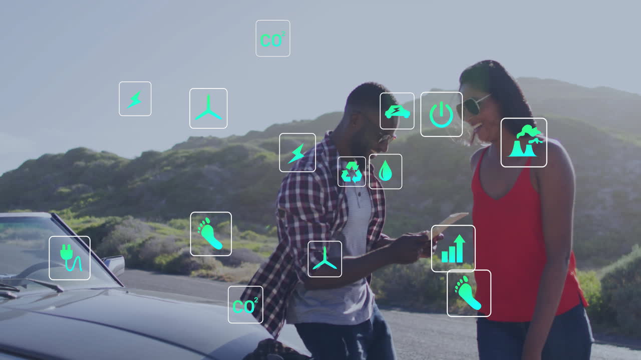 animación de íconos de la energía y la ecología sobre una feliz pareja diversa en coche en un viaje por carretera
