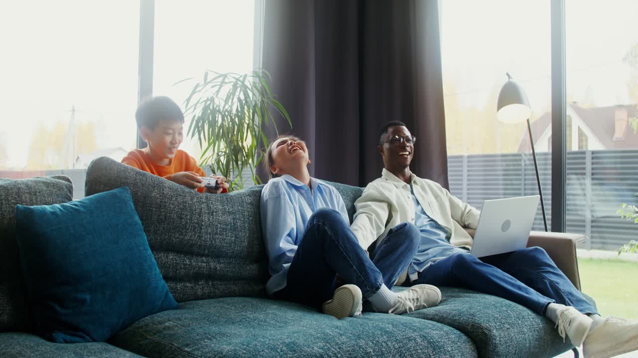 Family playing video games and using laptop at home