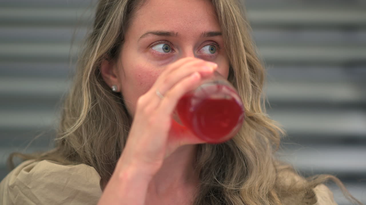 Woman drinking red juice in a glass at a restaurant