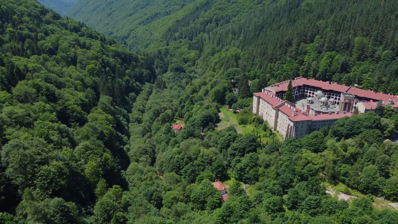 Cinematic drone video of Rila Monastery with endless forest in summer - Rila Mountains, Bulgaria