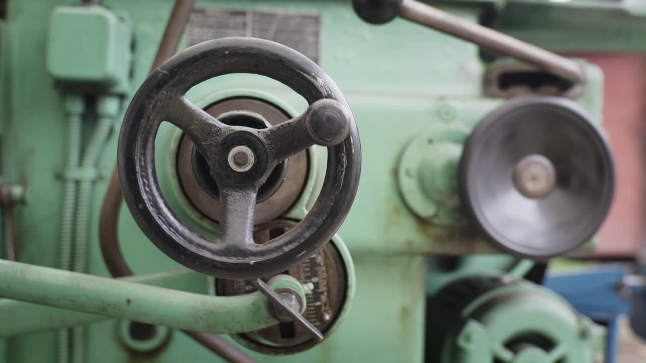 Detailní záběr na hoblovku na kov s mechanickými ručními koly v průmyslové dílně.