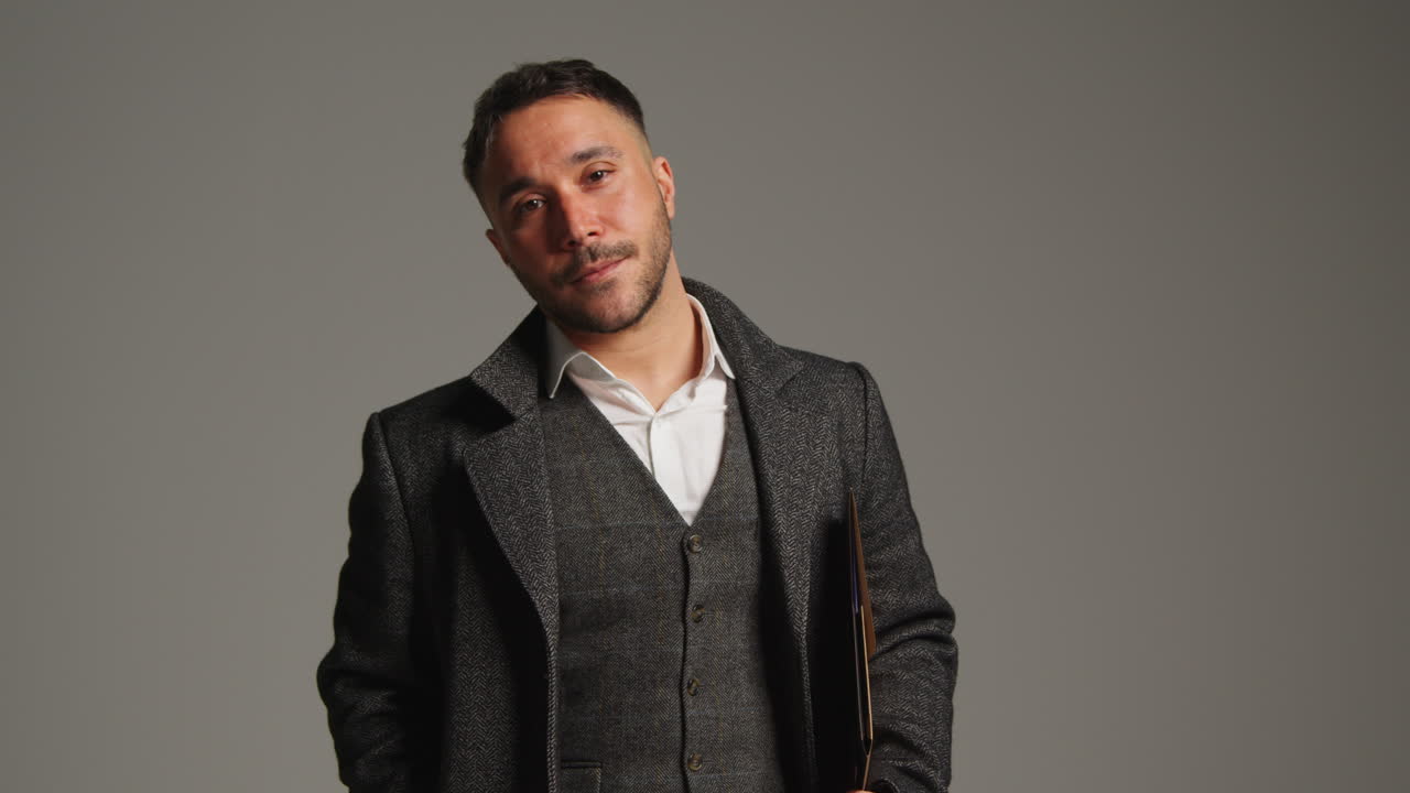 hombre de traje de pie frente a un fondo gris