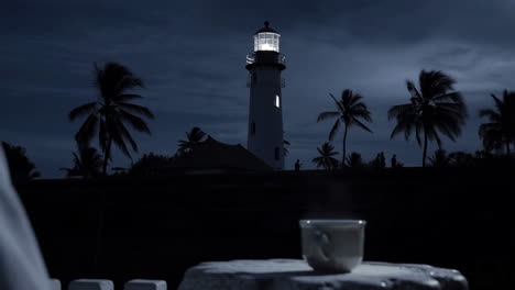 Lighthouse at Night with Palm Trees and Hot Drink