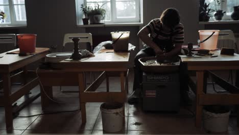 a young man works in a pottery workshop.