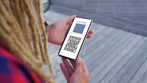 man with dreadlocks holding smartphone, covid vaccination certificate, eu flag and qr code on screen