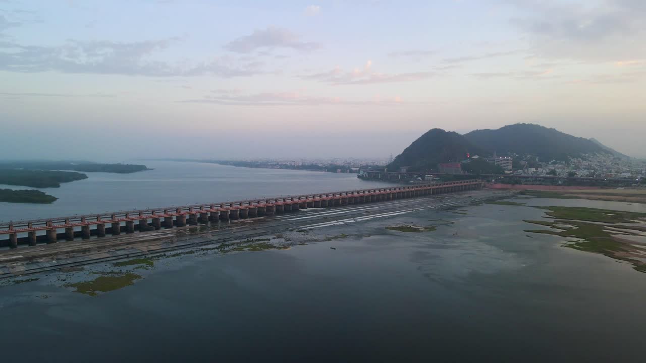 Stunning aerial drone shot of Vijayawada at dawn, with the sun rising over the horizon and casting light across the city.