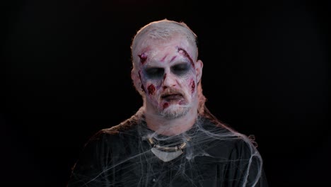 beängstigender mann mit halloween zombie blutig verwundetes make-up, gesicht schrecken ausdrücke, krämpfe