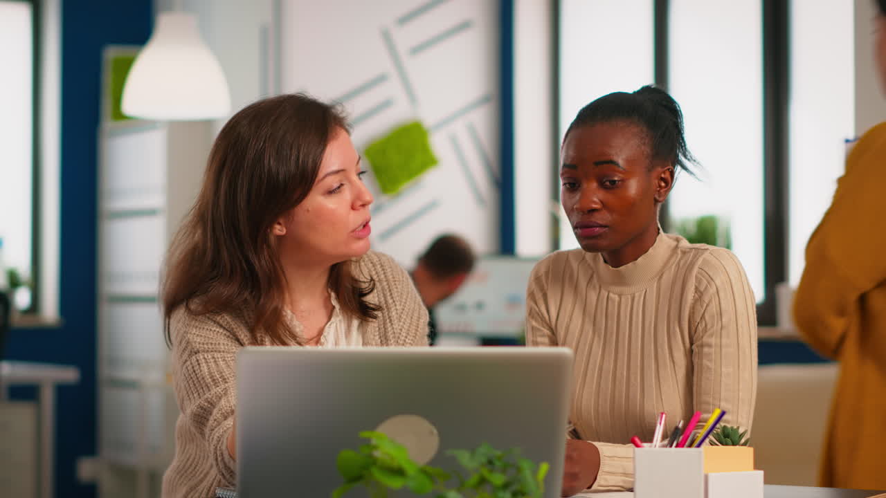 Company director explaining to black woman project results on laptop