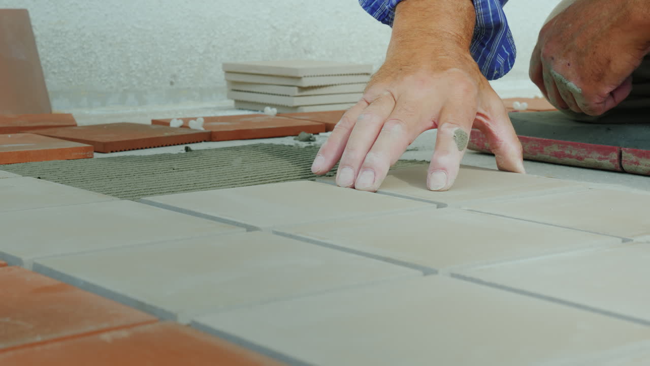 el constructor pone baldosas de cerámica en el suelo de la terraza abierta