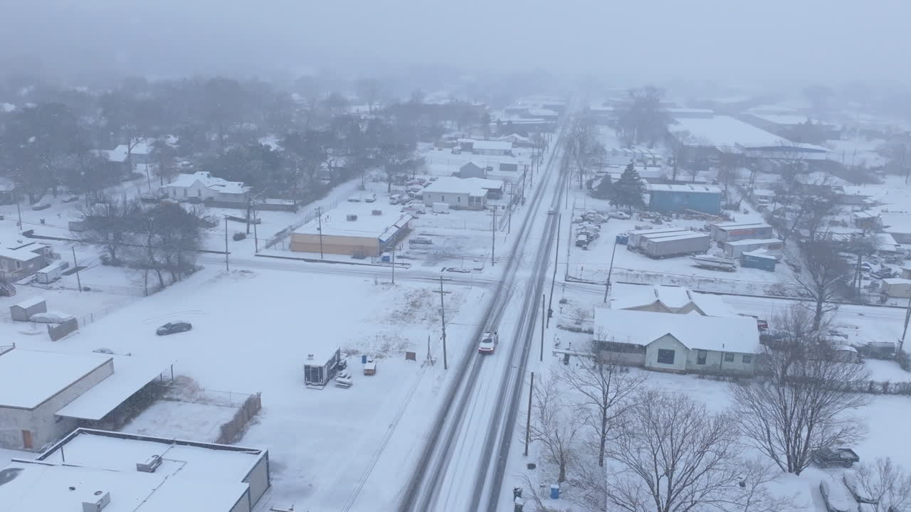Aerial footage flying over Dodds Ave during a snowstorm in Chattanooga, TN with a car in a ditch.