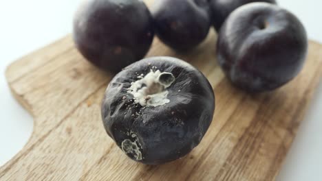 moldy plums on a wooden cutting board