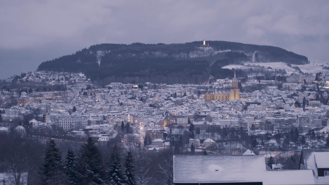 어두워지면서 눈으로 인 마을은 숲이 많은 언덕을 배경으로 한 계곡에 자리 잡고 있습니다.