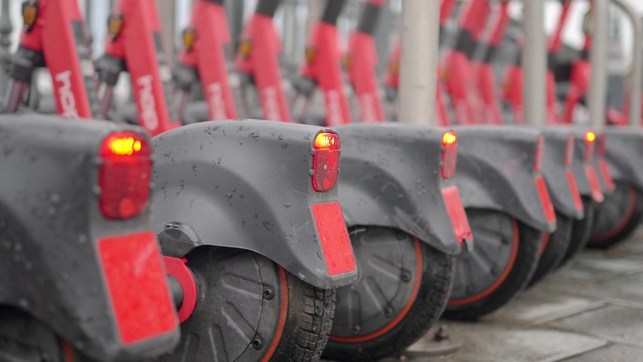Una fila de scooters eléctricos estacionados en la acera de la ciudad