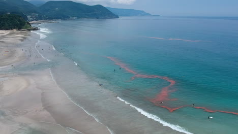 Turquoise-Ocean-And-Mountains-With-Tourists-Enjoying-The-Summer-Holidays---aerial-drone-shot