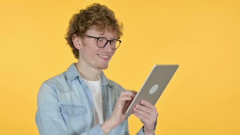 joven pelirrojo usando una tableta digital, fondo amarillo