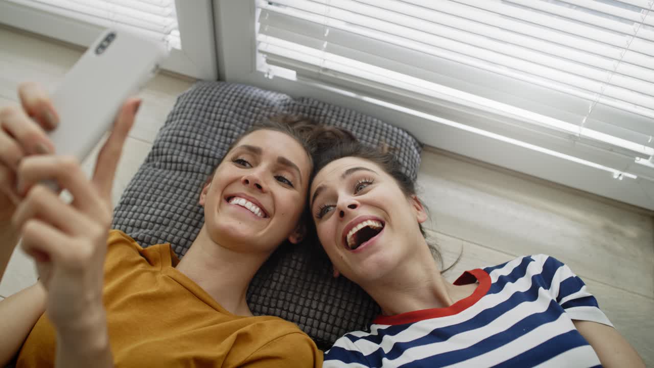 vista superior de dos chicas tomando selfies en el suelo