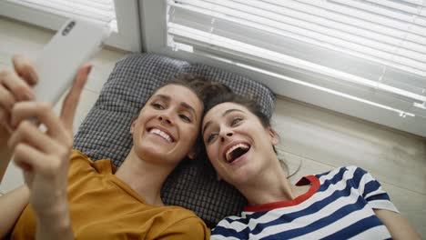 Top-view-of-two-girls-taking-selfie-on-the-floor