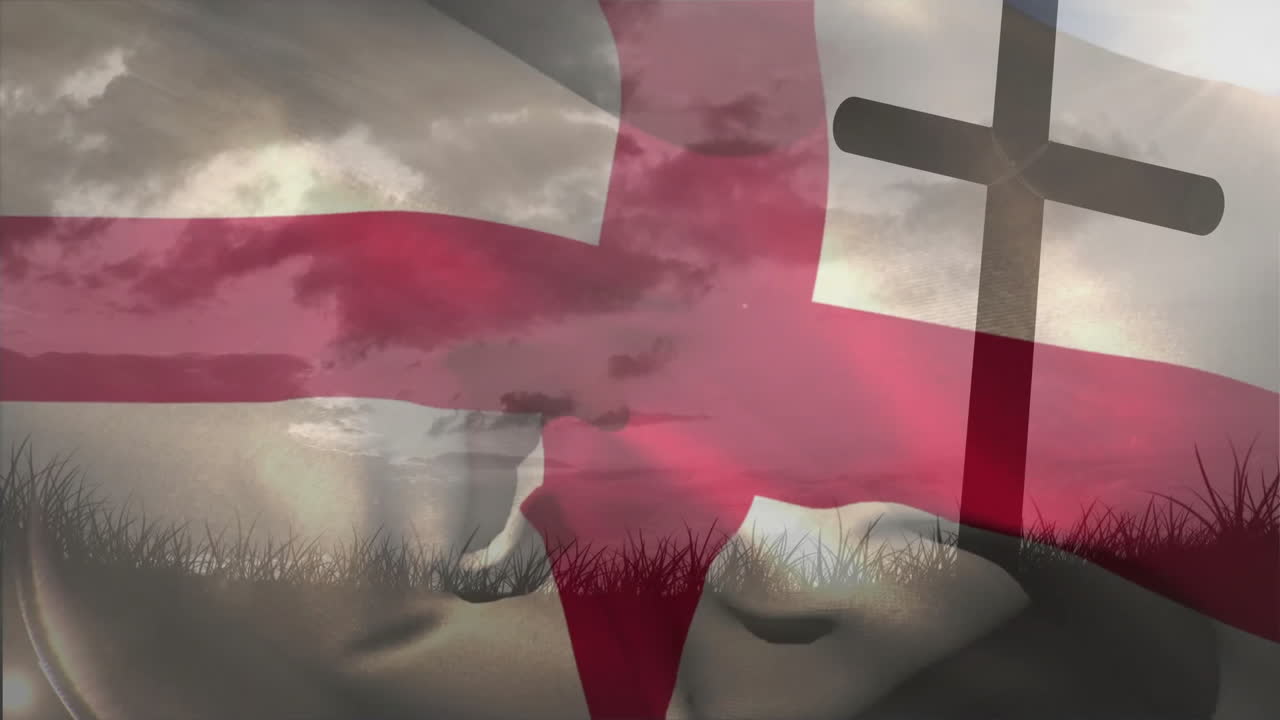 Cross silhouette with red cross flag waving in grassy field under cloudy sky