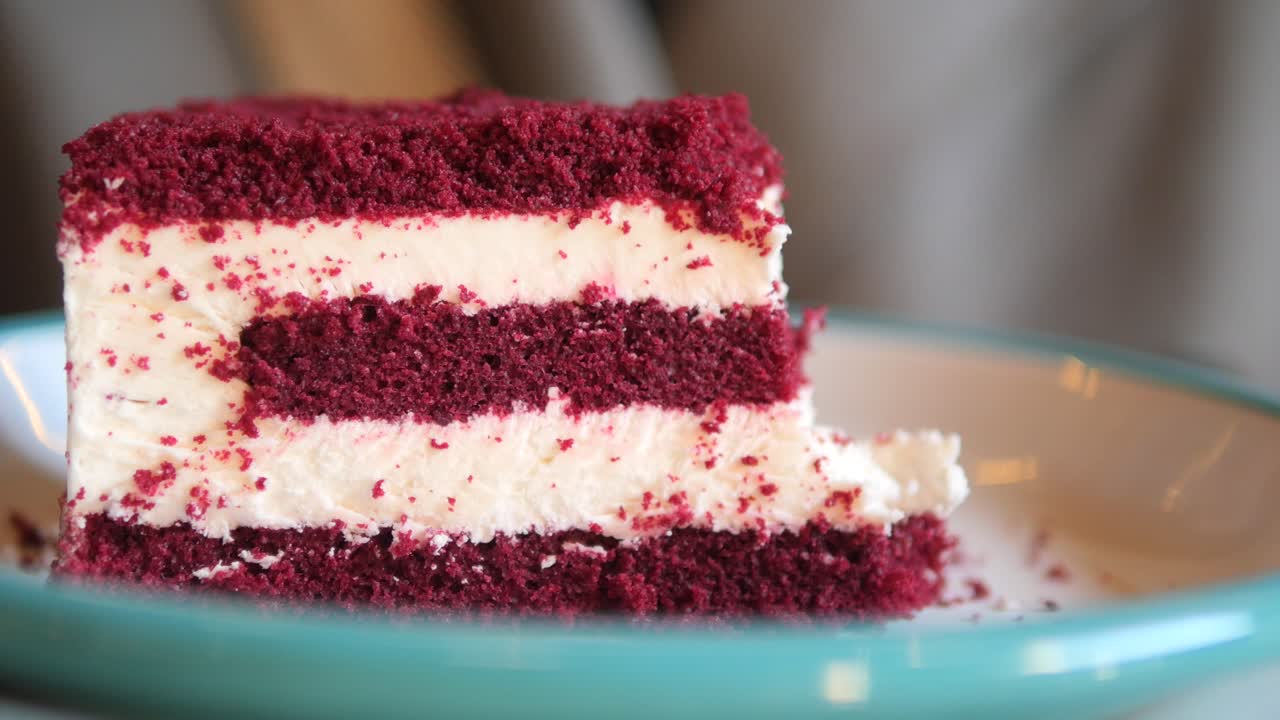 ein stück roter samtkuchen mit creme-käse-glasur