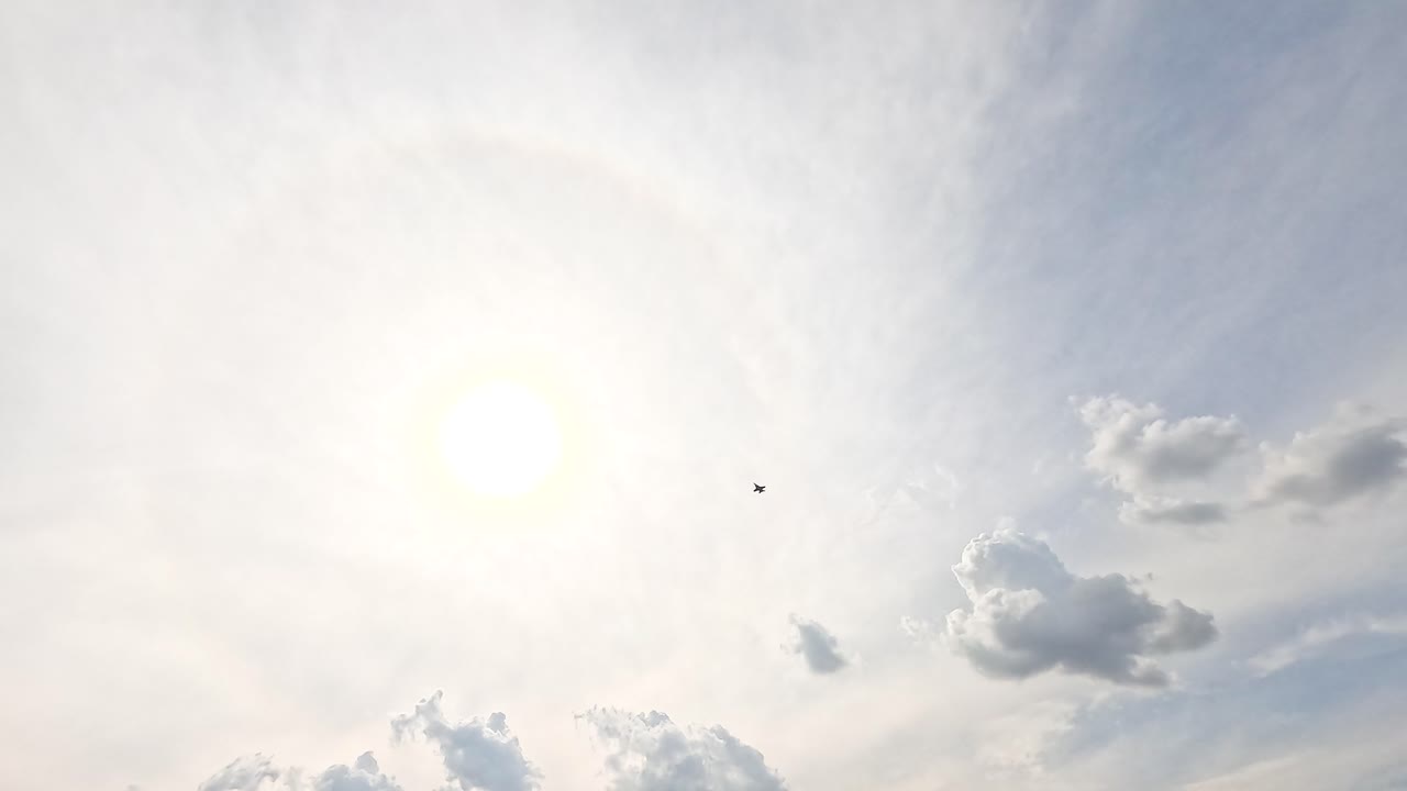A jet flies through a bright sky with scattered clouds, creating a dynamic scene at the Avalon Airshow in Geelong, Australia