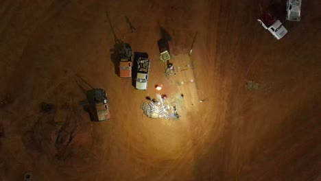 ascending shot of oval dirt race car track crew fueling bonfire on the infield