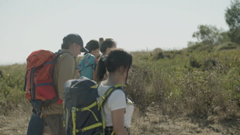 family with backpacks on hiking adventure on warm summer day