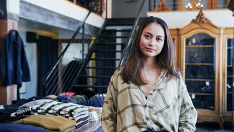 Retrato-De-Una-Sonriente-Propietaria-De-Una-Tienda-De-Moda-Parada-Frente-A-Una-Exhibición-De-Ropa