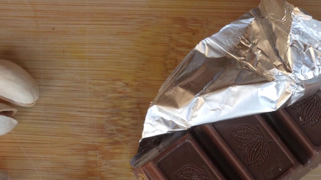 Barra de chocolate parcialmente envuelta, evocando indulgencia y lujo.
