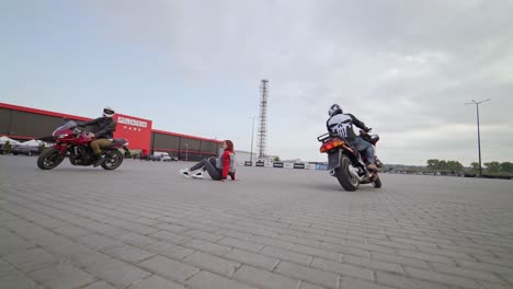 bikers riding around girl. view of bikers riding on motorcycle around girl on parking