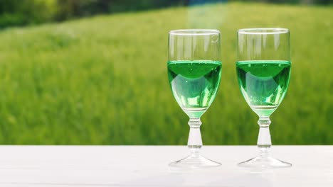 Two-Glasses-With-Green-Lemonade-On-A-Background-Of-A-Green-Lawn-In-A-Spring-Garden