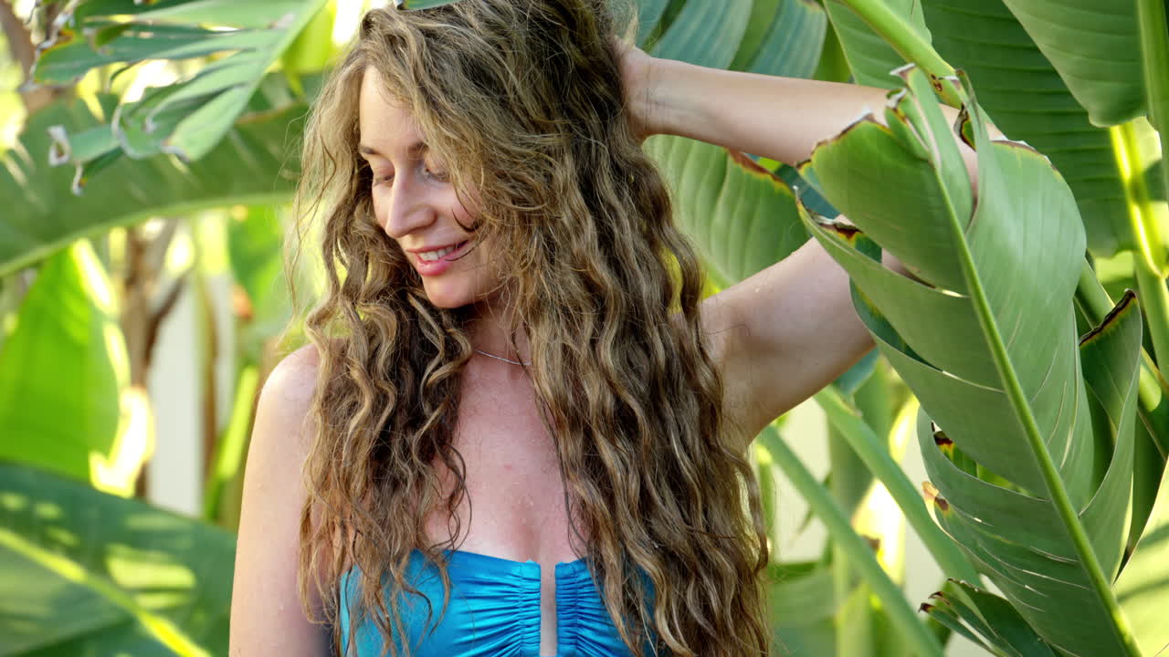 Woman playing with palm tree leaves at the beach in Cyprus, hiding