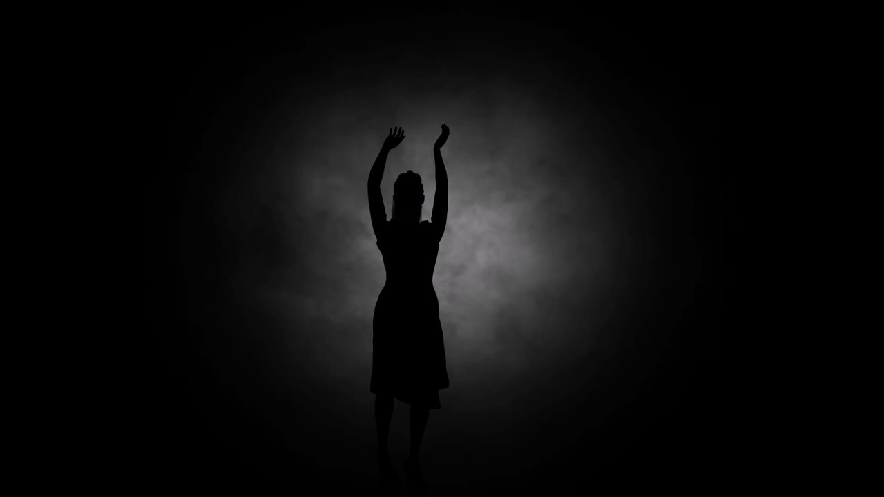 un baile juvenil moderno realizado por una silueta femenina elegante y sexy, en el humo contra el telón de fondo de los focos