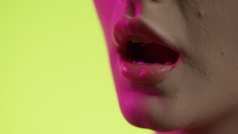 close up de la boca de la mujer comiendo masticando oblea con colorida iluminación de estudio, toma de estudio
