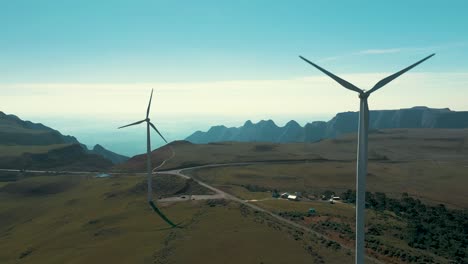 two wind turbine generators on top of a plateau near mountains and canyons