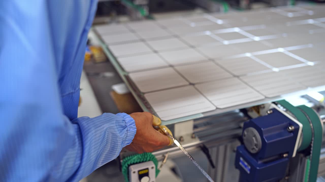 Worker's hands measuring solar panel. Factory for producing solar cells indoors. Close-up.