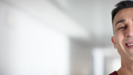 portrait of happy biracial male doctor smiling in hospital, copy space, slow motion