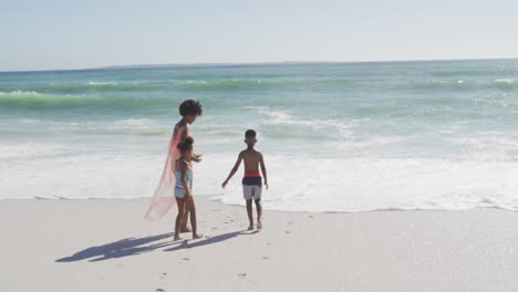 Smiling-african-american-mother-with-children-wearing-swimming-suits-on-sunny-beach